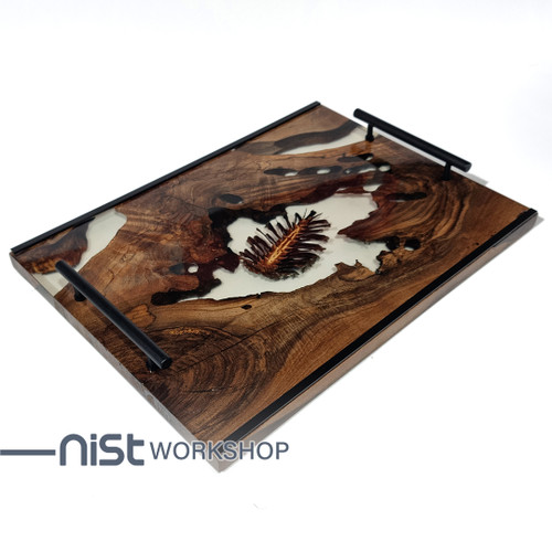 سینی چوبی دستساز از چوب گردو و رزین شفاف با میوه کاج خشک شده طبیعی ، دارای دستگیره فلزی مشکی و طراحی مدرن.